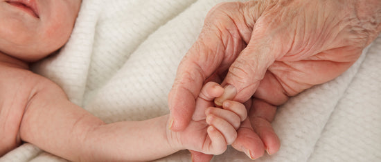 Baby reaching out to older hand