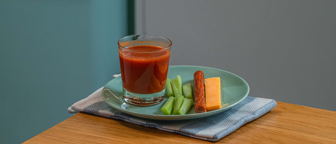 Cheddar cheese stick, uncured beef stick, celery sticks, and vegetable juice
